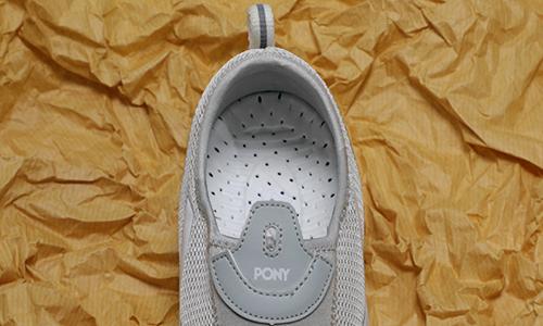 نمای نزدیک کفی سفید رنگ کفش طبی کفش پونی همراه با منافذ متعدد مشکی برای گردش بهتر هوا